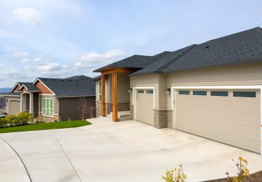 New custom built houses in Happy Valley Oregon suburban neighborhood with car garage driveway and manicured front lawn